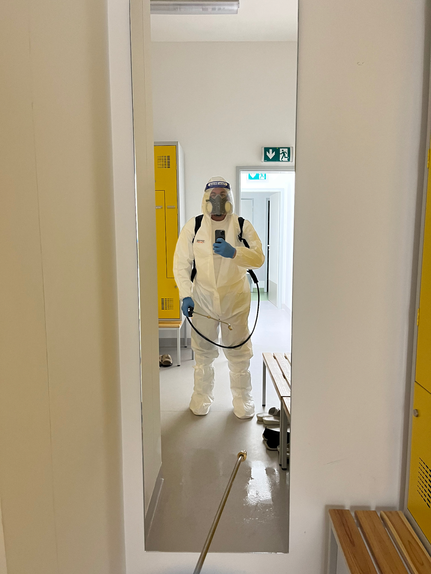 Technik PEDRO SERVICE v kompletnom ochrannom obleku s respirátorom pri dezinfekcii šatní